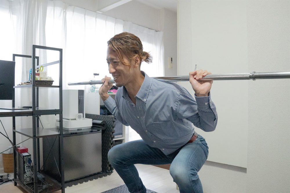 スクワットの動きを実演するFootworkのトレーナー